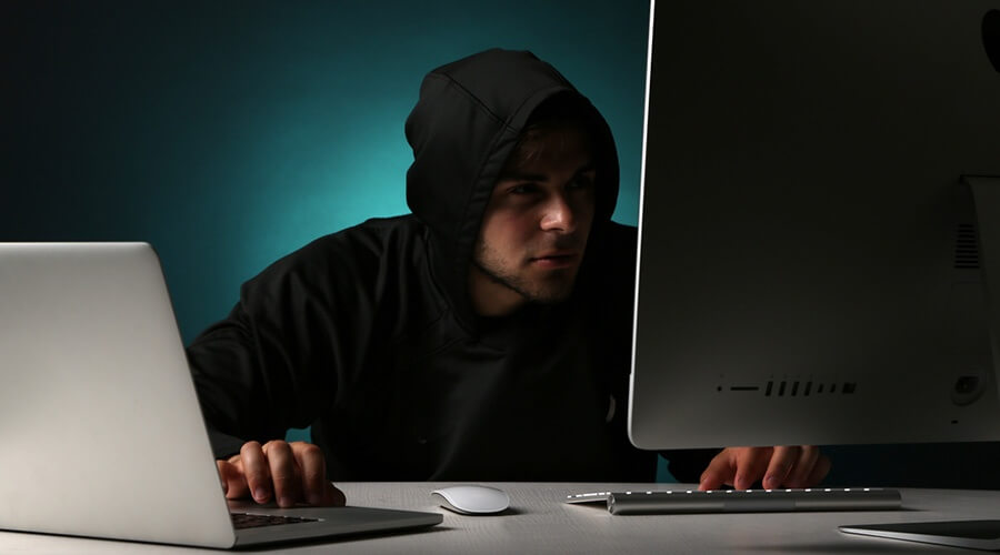 Hooded person at a computer